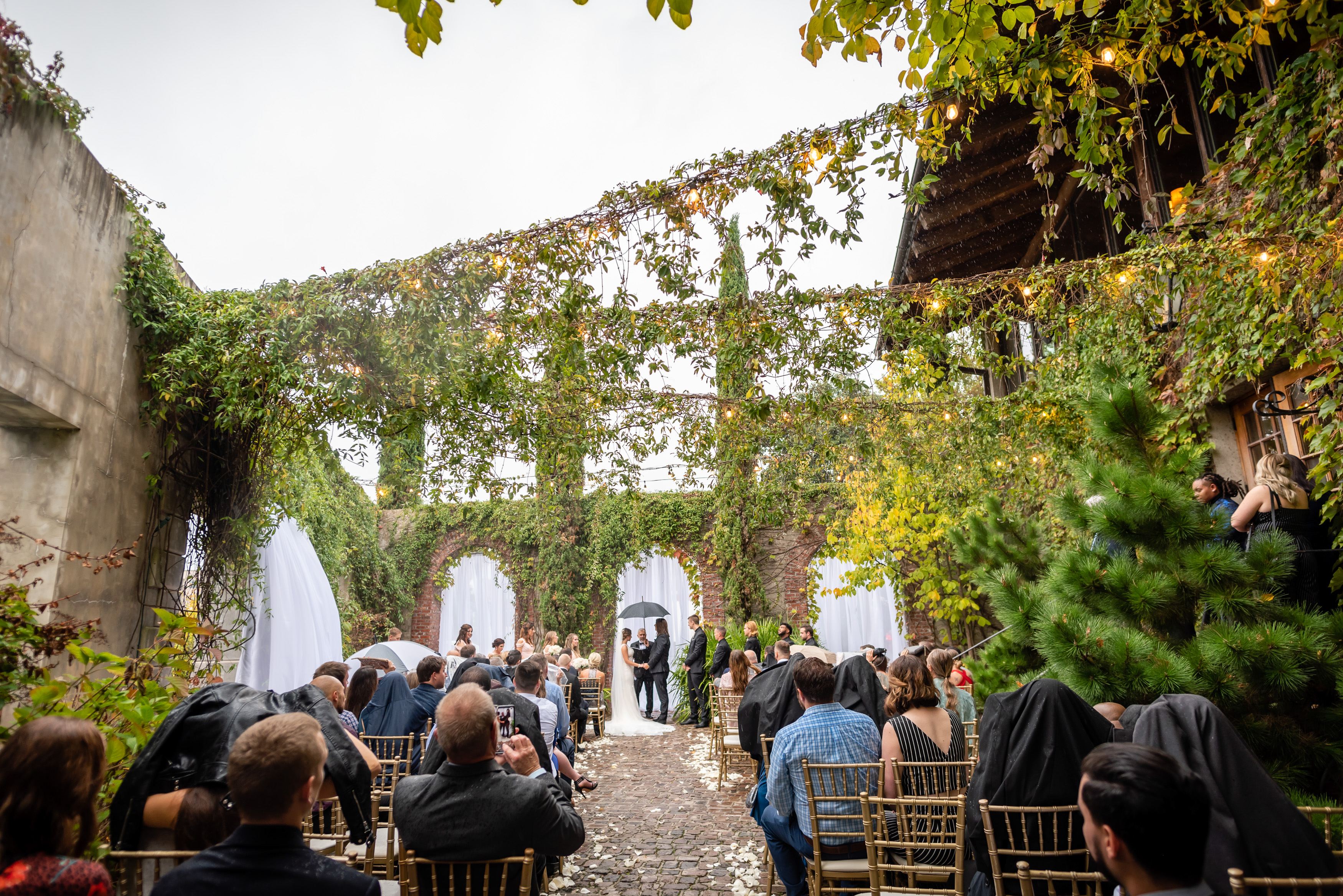 Outdoor reception under hanging ivy and stringlots in the rustic courtyard at Summerour Studio in Atlanta GA