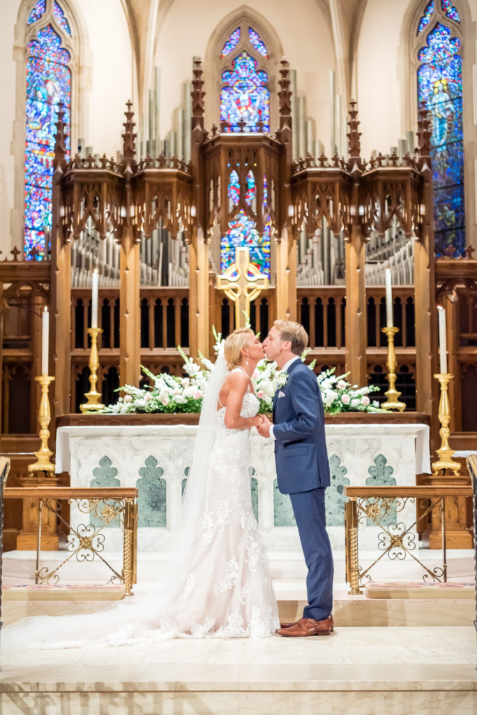 Bride and groom kissing at the alter at The Cathedral of St Philp in Atlanta GA
