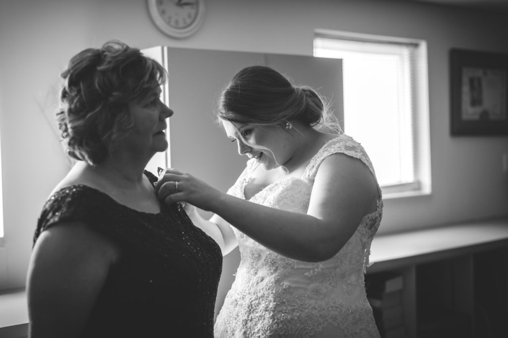 Bride pinning a boutonniere onto her mother's dress