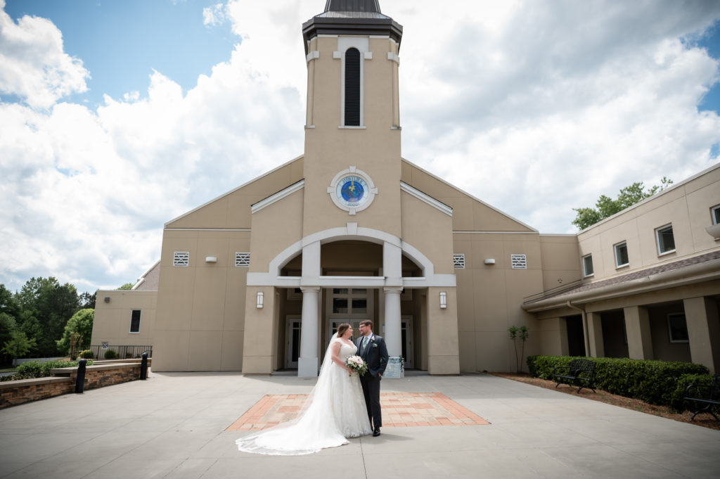 Bride and groom standing in front of St Andrew Catholic Church
