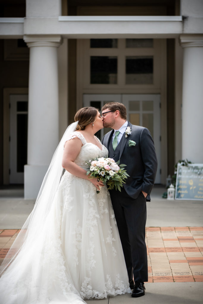 Bride and groom kissing in front of St Andrew Catholic Church