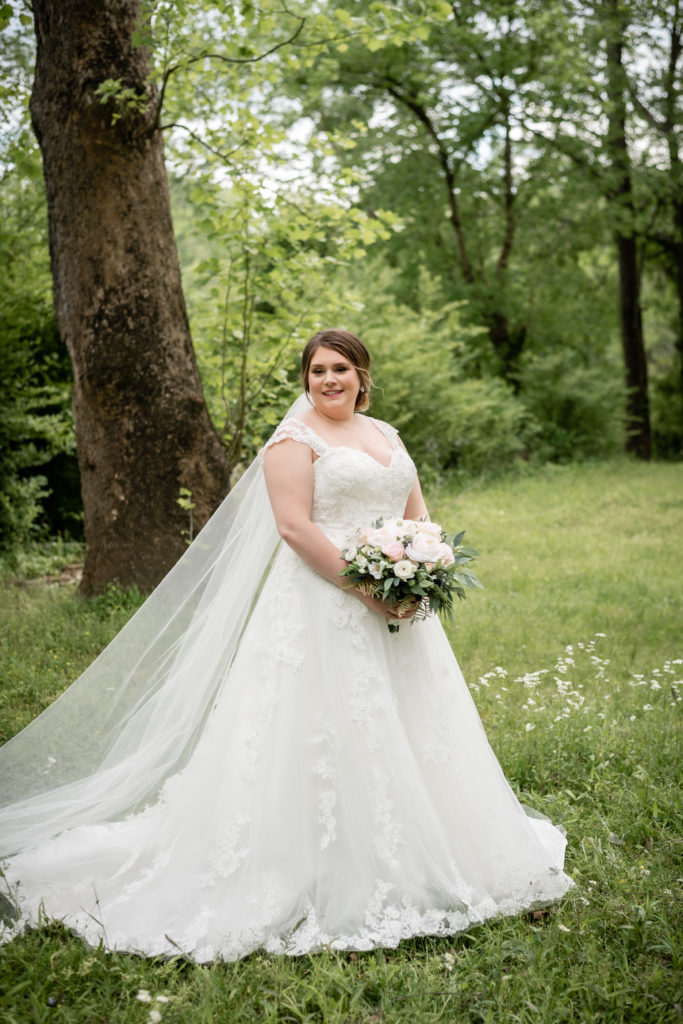 Bride holding her bouquet and looking at the camera while standing in the park in Roswell, GA