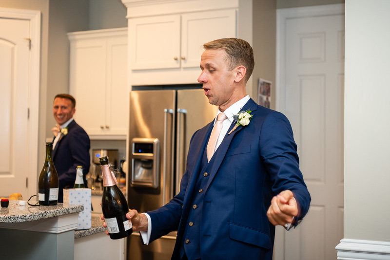 groom popping the cork off of champagne before toasts in Charlotte North Carolina