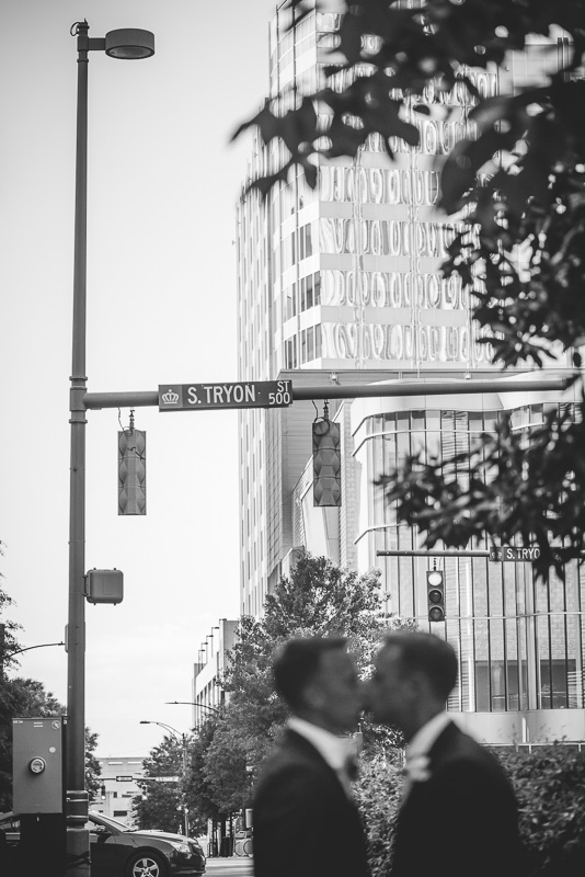 Two grooms kissing under street sign in Charlotte North Carolina