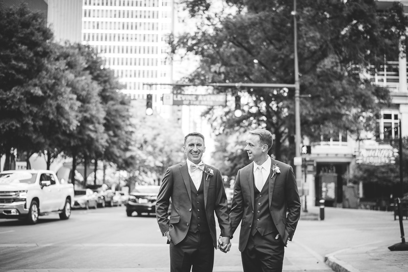 Two grooms holding hands under street sign in Charlotte North Carolina