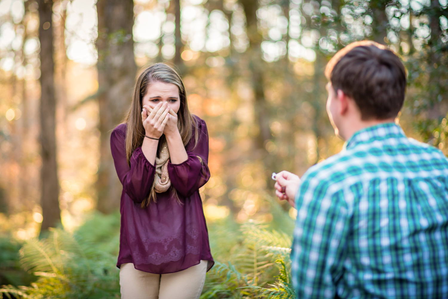 Girl holding her hands to her face as she is being proposed to by her boyfriend at Callaway Gardens in Pine Mountain, GA