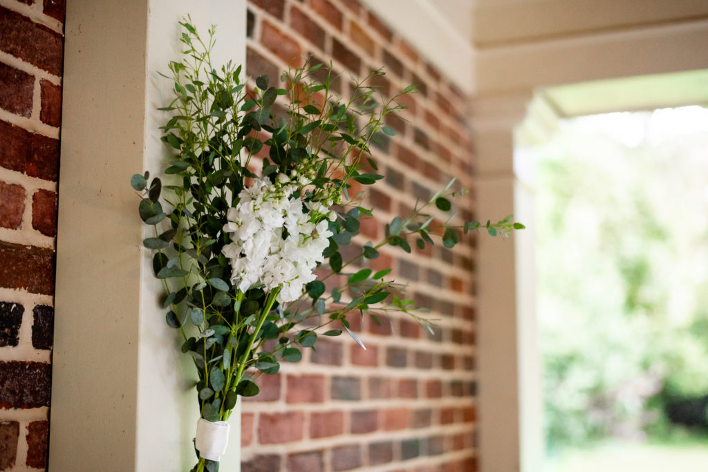 Greenery and white florals hung on the wall at ceremony site at intimate, backyard wedding in Marietta GA