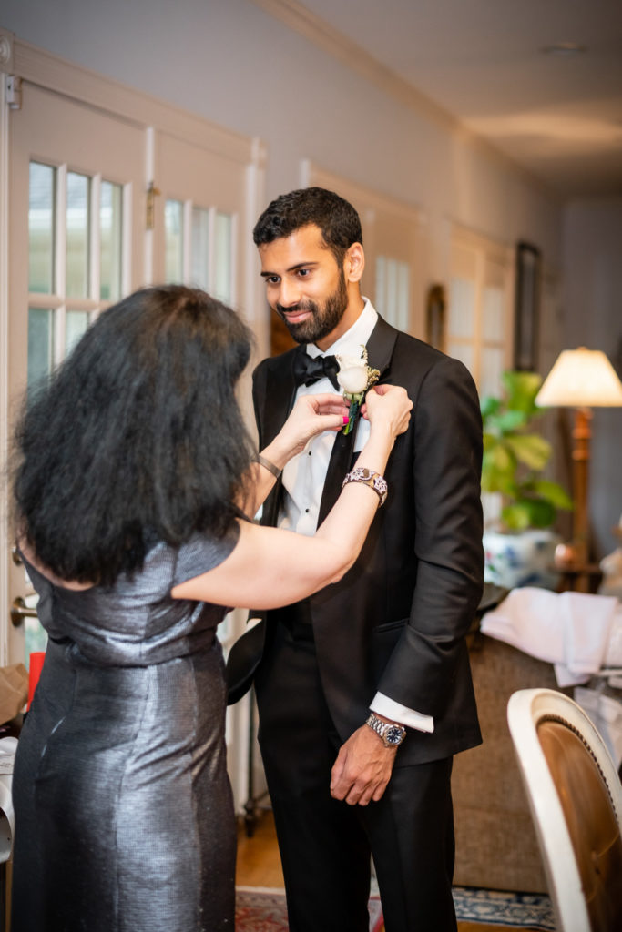 Mother of the groom pinning boutonnière on groom at intimate, backyard wedding in Marietta GA