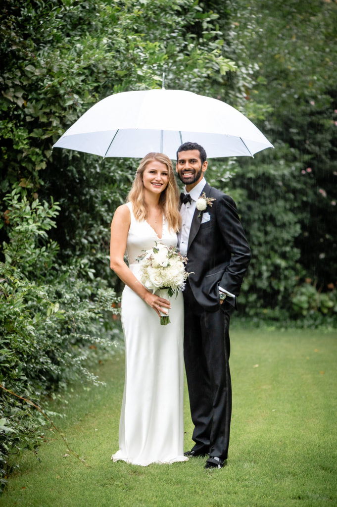 Bride and groom posing with umbrella for portraits at at intimate, backyard wedding in Marietta GA