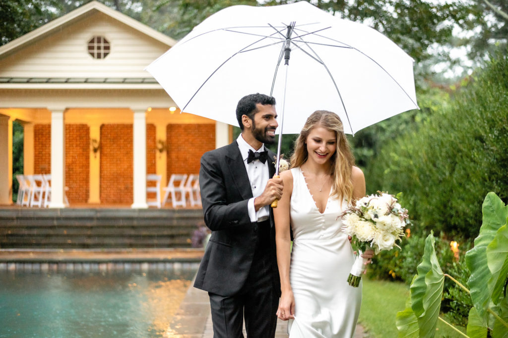 Bride and groom walking poolside with umbrella at intimate, backyard wedding in Marietta GA