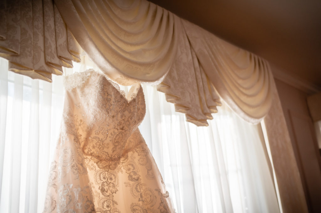 Photo of wedding dress hanging on window at wedding at The Gavi Estate and Barn in Forsyth GA