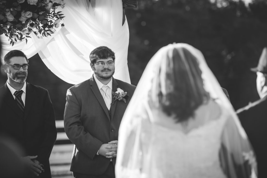 groom gazing at bride walking down the aisle at wedding at The Gavi Estate and Barn in Forsyth GA