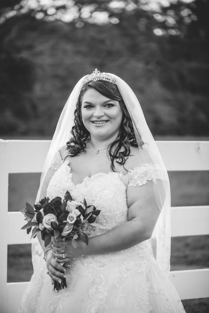 Portrait of bride standing by white fence at wedding at The Gavi Estate and Barn in Forsyth GA