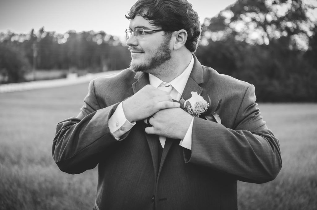 Portrait of groom standing in open field at sunset at wedding at The Gavi Estate and Barn in Forsyth GA