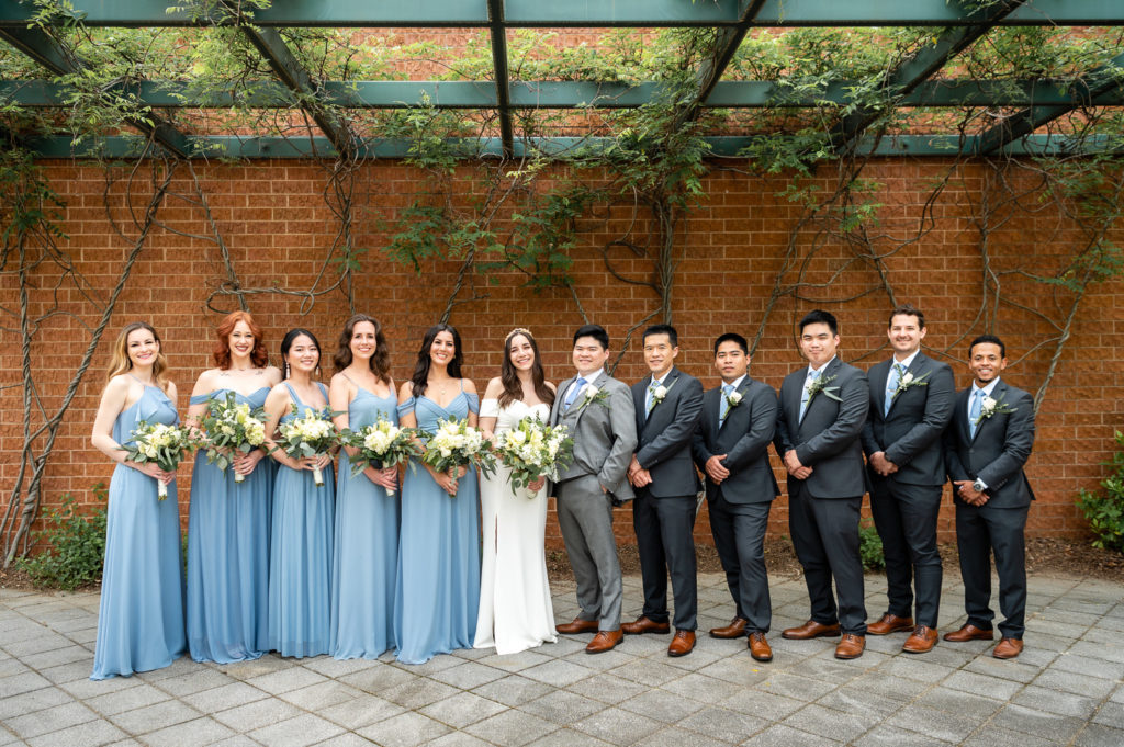 entire bridal party in front of brick wall on the wedding day at The Hudgens Center for Art and Learning in Atlanta Georgia