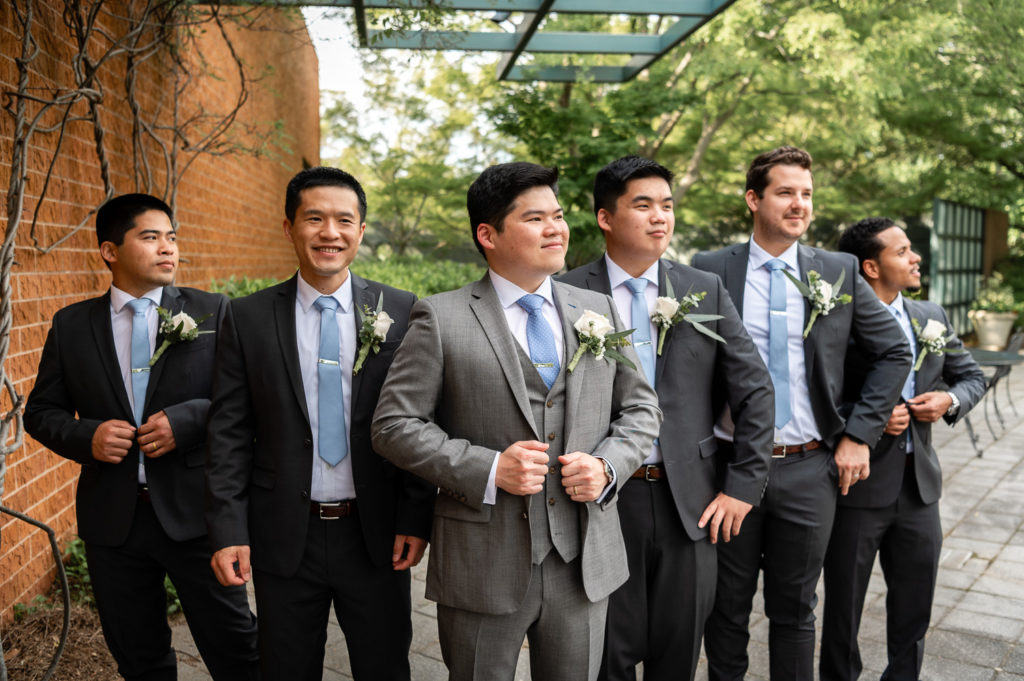 groom and groomsmen straightening suits in the garden on the wedding day at The Hudgens Center for Art and Learning in Atlanta Georgia
