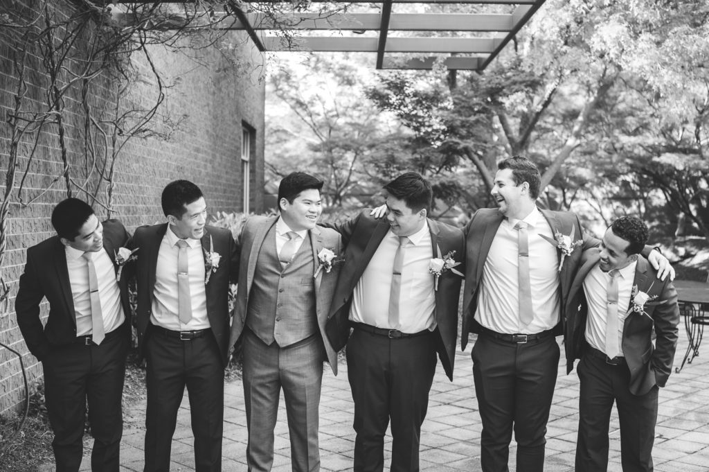 groom and groomsmen laughing at each other in the garden on the wedding day at The Hudgens Center for Art and Learning in Atlanta Georgia