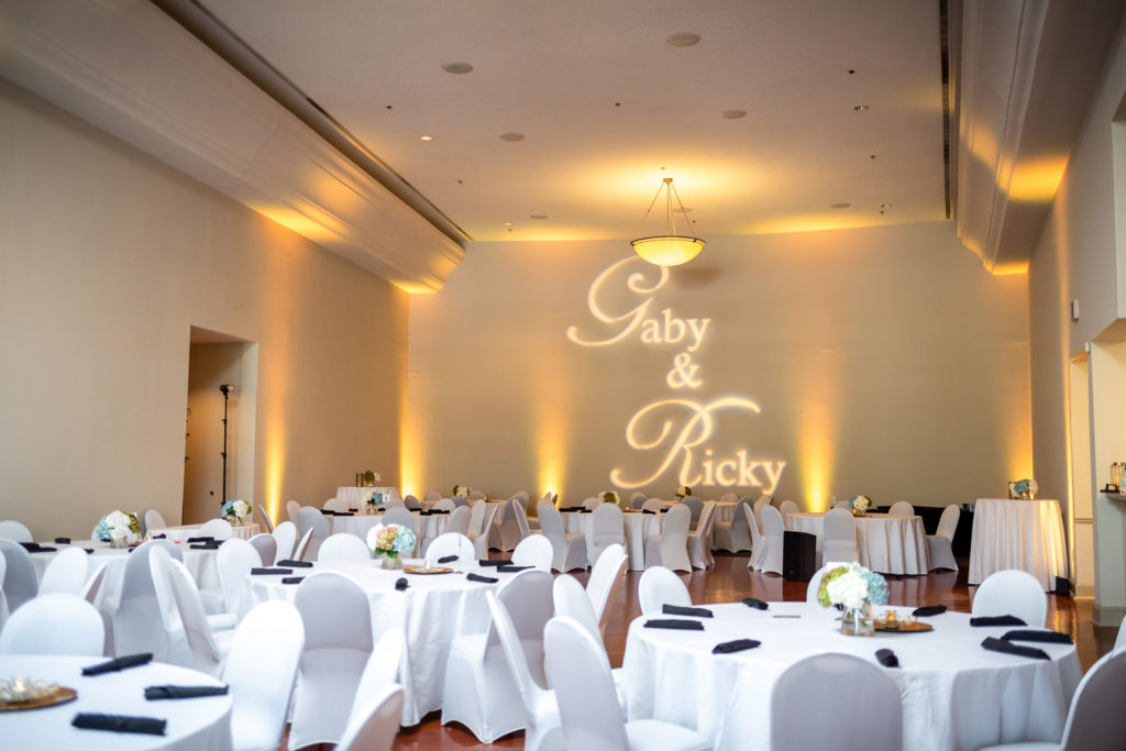 view of the reception room with banquet tables and bride and groom's name projected on the wall on the wedding day at The Hudgens Center for Art and Learning in Atlanta Georgia